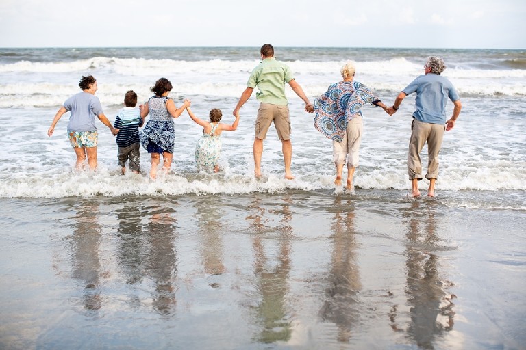 Three generations splash in the Atlantic Ocean together at the end of their Charleston beach photo session.